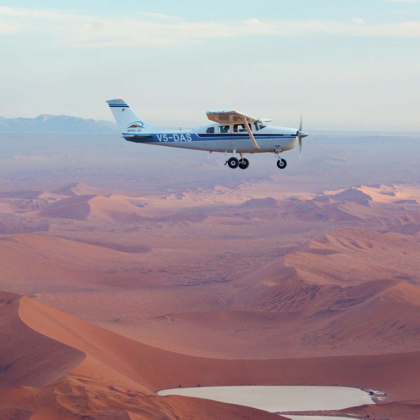 A light aircraft flying low over the dunes of the Namib