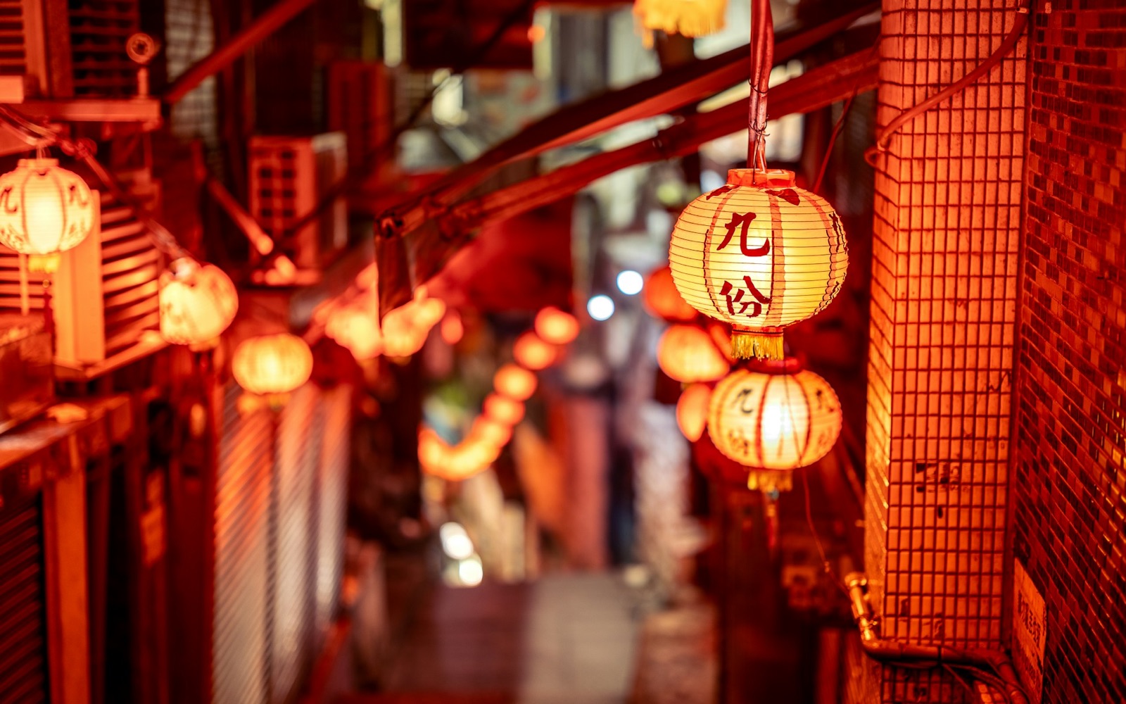 Red lanterns strung along a narrow street at night in Jiufen