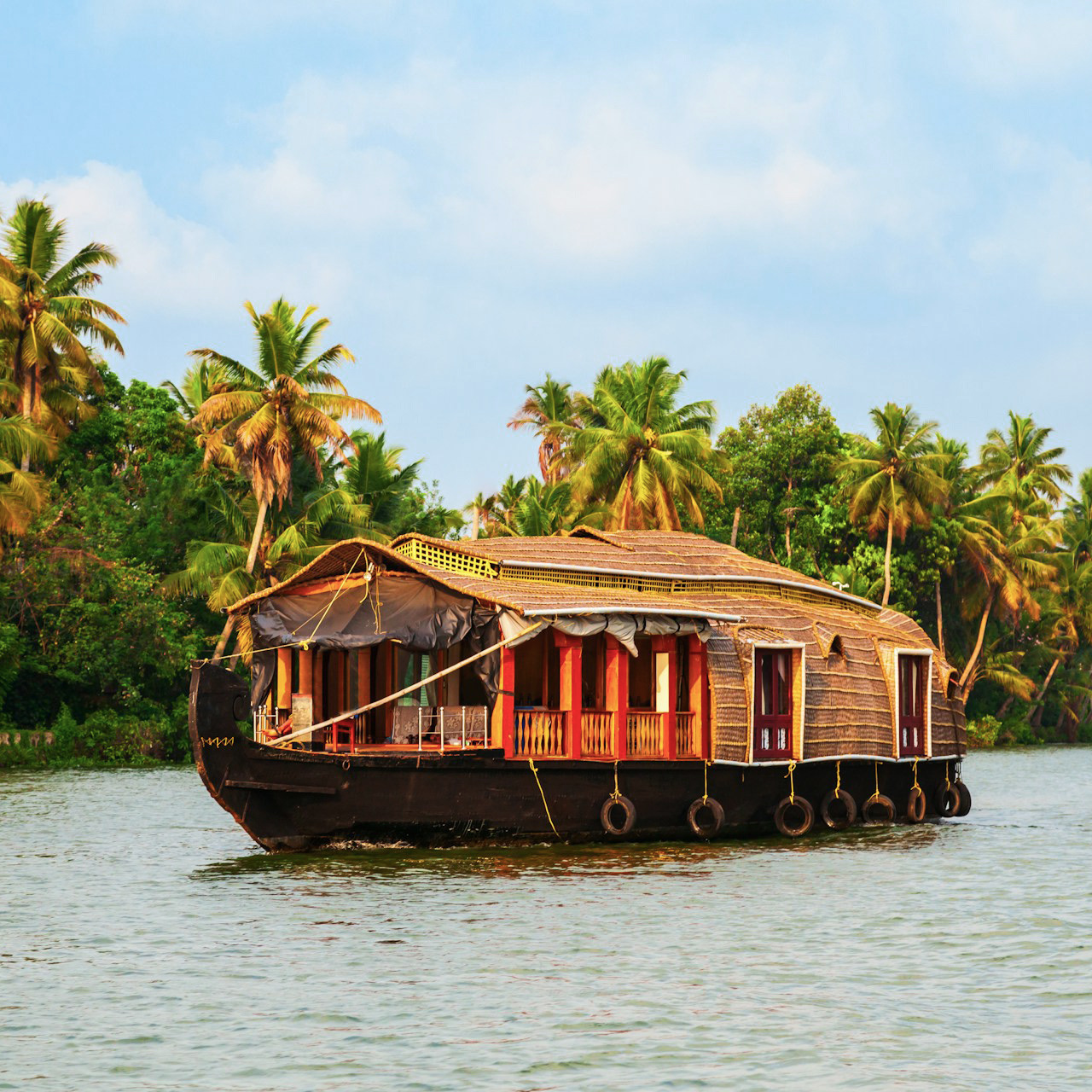 A thatched houseboat on the Kerala backwaters, palms behind