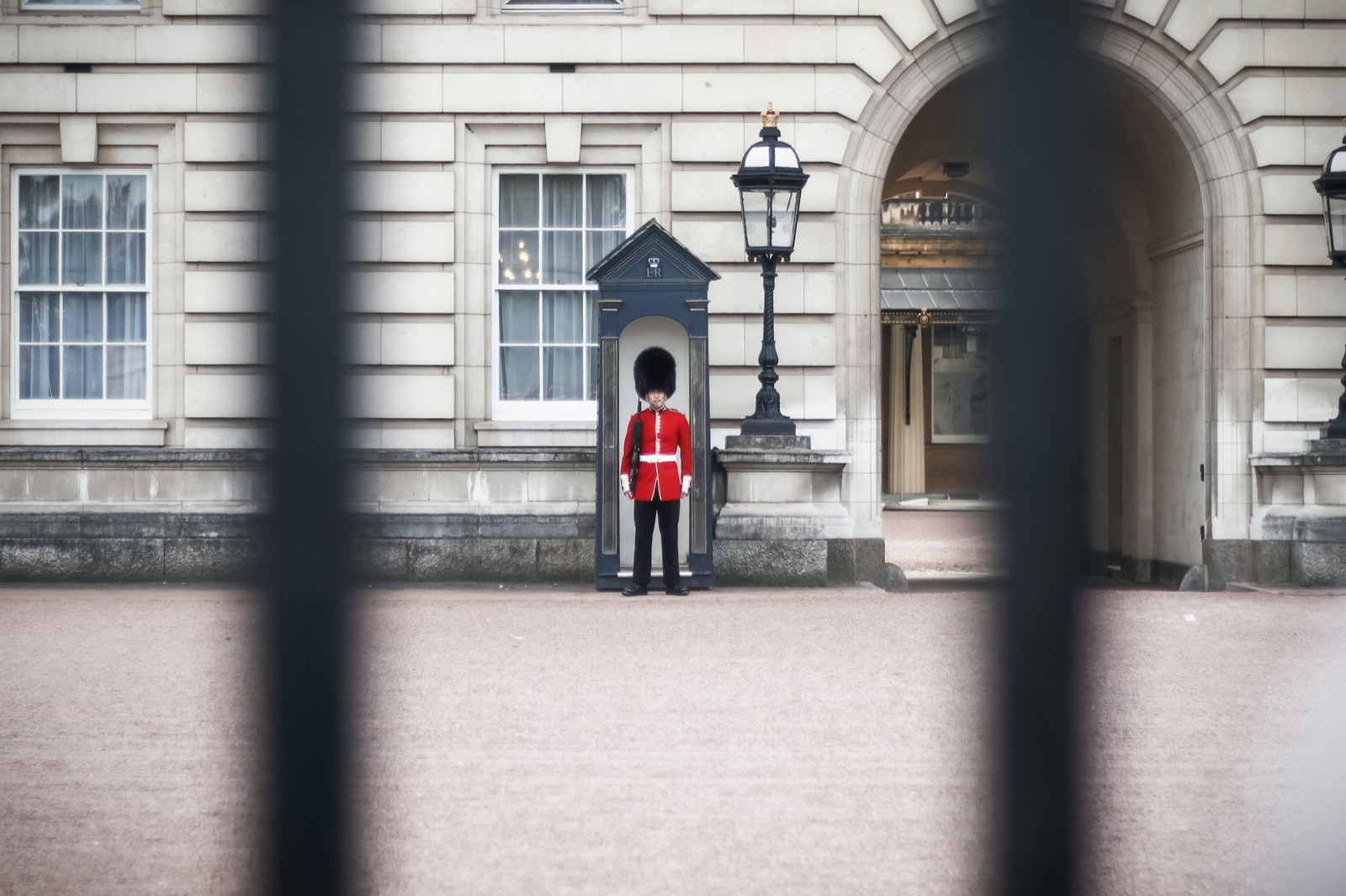 A guardsman outside Buckingham Palace, seen through the railings