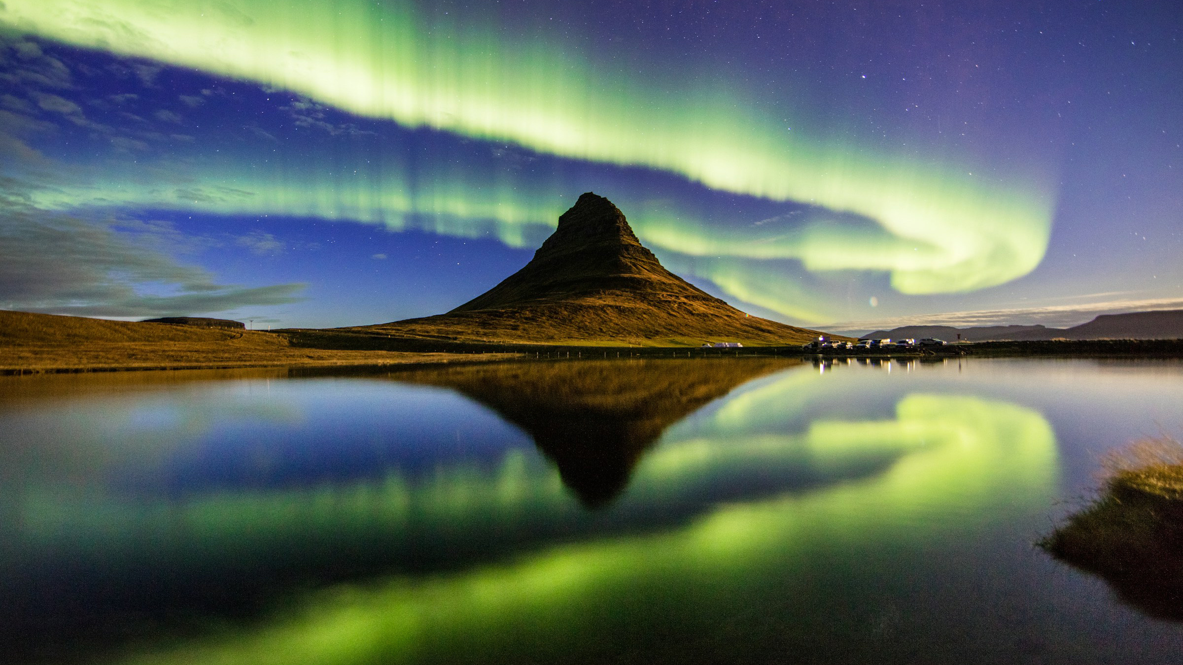 The northern lights over Kirkjufell and a still lake in Iceland