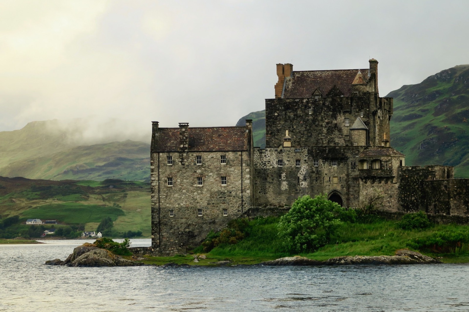 A stone castle on a loch in the Scottish Highlands under low cloud