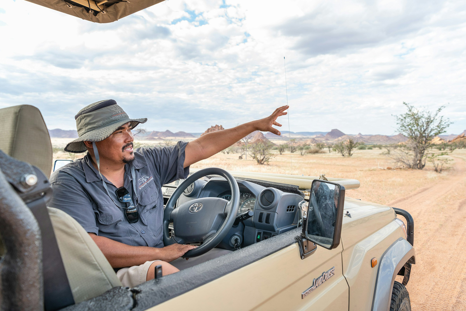 A guide pointing something out from an open vehicle in the Namibian desert