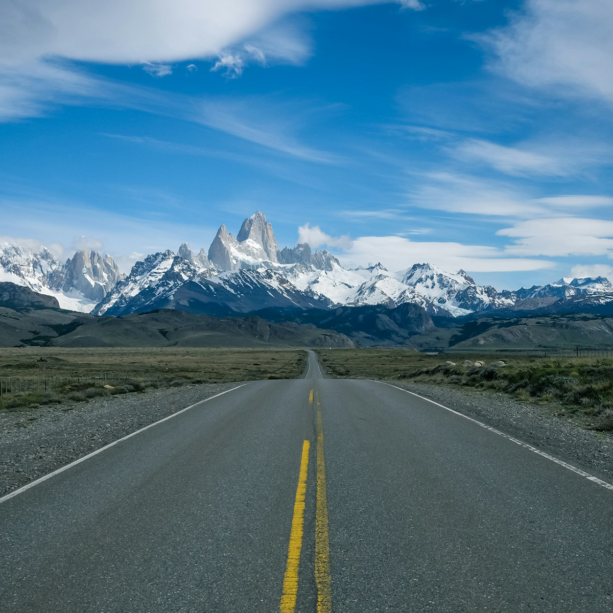 An empty road running straight toward the Patagonian peaks