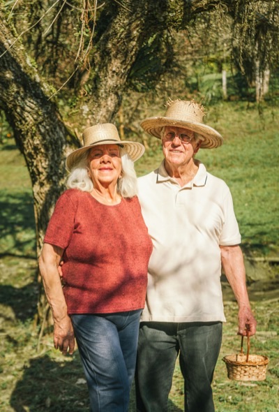 Two travelers in straw hats walking under a tree
