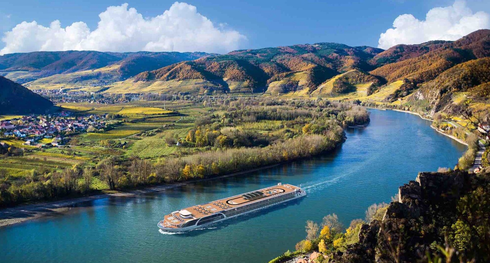 A river boat rounding a bend in the Danube below terraced vineyards